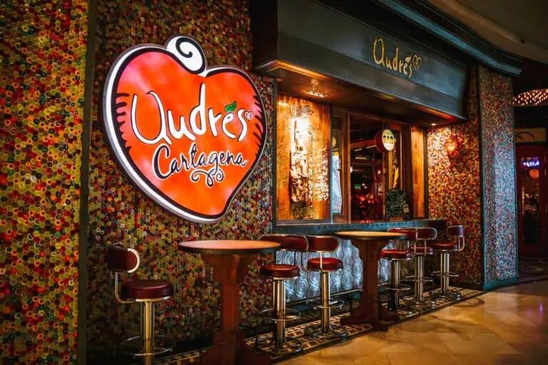 卡塔赫纳餐厅，外墙装饰着彩色纽扣马赛克，并挂有复古风格的“Oudes Cartagena”霓虹灯招牌。