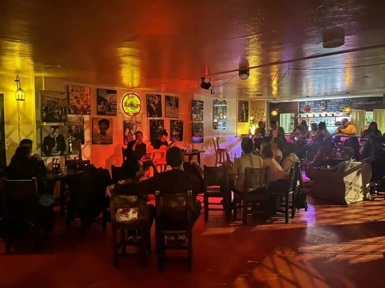 A bar and restaurant with a live music atmosphere, decorated with jazz and cultural posters, in a cozy space with warm lighting, ideal for events and social gatherings in Colombia.