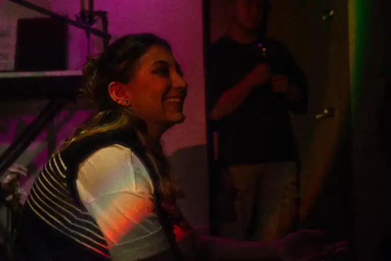 Disfrutando evento en ambiente nocturno con iluminación vibrante, joven mujer sonriendo y participando en actividad social en evento empresarial o de networking en Colombia.