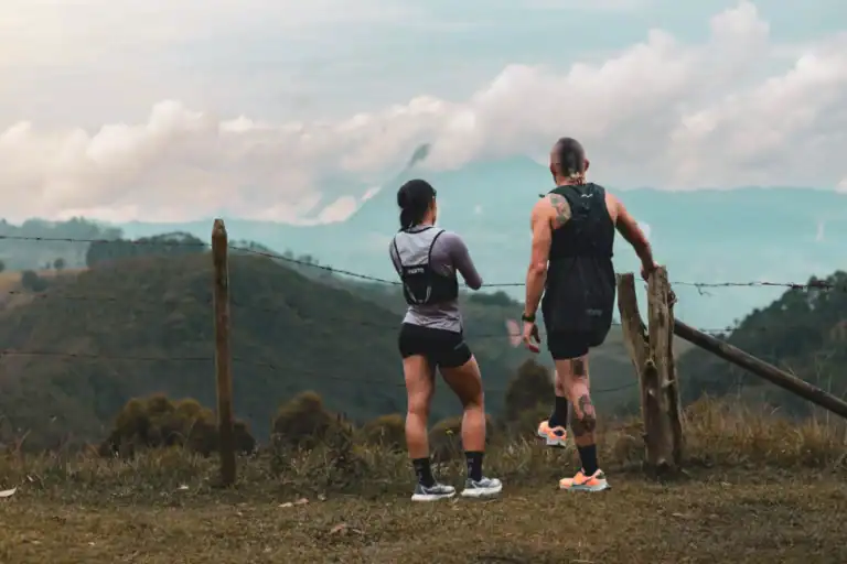 Atleta corriendo en montaña, disfrutando de la naturaleza con ropa deportiva y mochila, en un paisaje de montañas y nubes, promoviendo eventos deportivos y actividades al aire libre en Colombia.