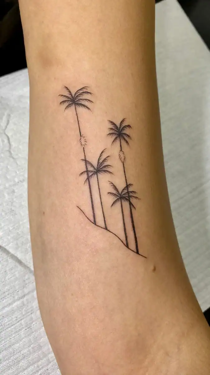 Palmeras en tatuaje minimalista, diseño delicado en la piel. Tatuaje de estilo sencillo y elegante con palmeras y línea de tierra, perfecto para amantes de la naturaleza y el estilo tropical.