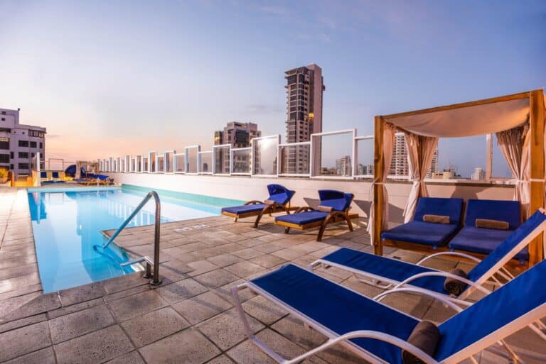 Piscina en azotea con tumbonas y vista urbana en sunset, espacio ideal para eventos y relax en la ciudad.