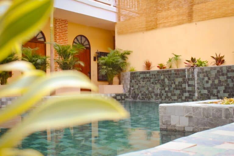 Amplia piscina en hotel boutique con diseño moderno, rodeada de plantas tropicales, ideal para eventos y reuniones empresariales en un ambiente relajante y exclusivo en Colombia.