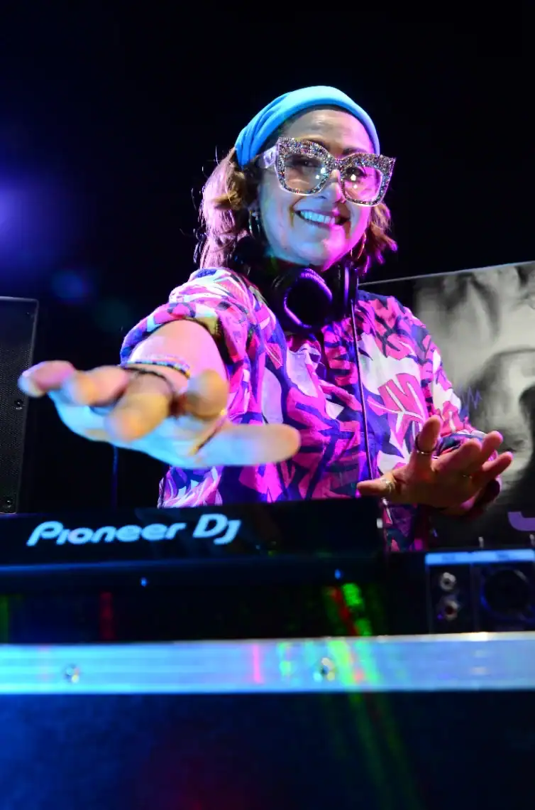 DJ mujer con gafas de cristales brillantes y auriculares en fiesta en vivo, música, entretenimiento, evento social, ambiente vibrante, discoteca, fiesta moderna, música electrónica.