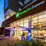 Holiday Inn Express Medellín modern hotel facade with night lighting and green areas, ideal for lodging and events in Medellín.