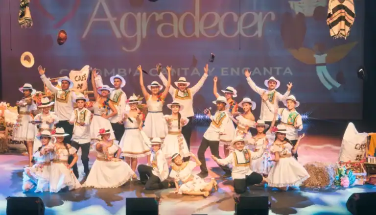 Caballos de baile folklórico colombiano en escenario con fondo colorido y decoraciones tradicionales, celebración cultural con niños y adultos en vestimenta típica colombiana, evento de festividad y tradición agraria en Colombia, evento cultural colombiano, foto de presentación artística en evento tradicional colombia.