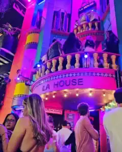 Vibrante ambiente en un evento en La House, con iluminación de colores y personas socializando, ideal para promover eventos y experiencias en lugares de ocio y entretenimiento en Colombia.
