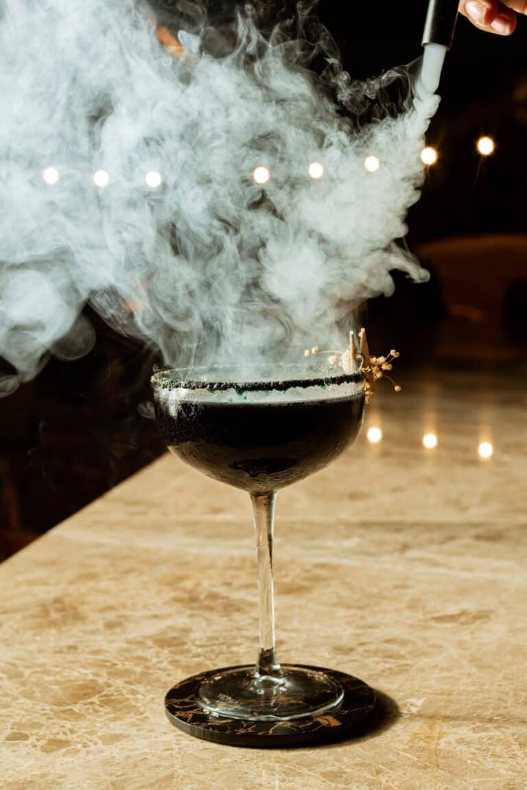 Vaso de cóctel con humo de hielo seco en un ambiente de fiesta, resaltando el concepto de eventos y celebración con estilo.