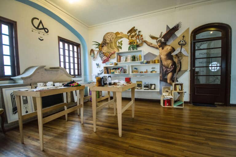 Coloridas paredes con arte mural, mobiliario moderno y objetos decorativos en una sala de eventos con buena iluminación y ambiente acogedor ideal para actividades culturales y creativas.