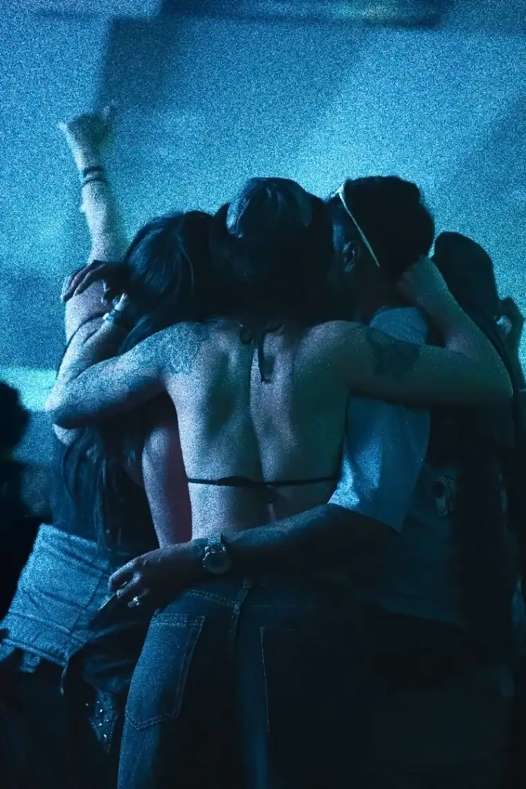 Escena romántica en fiesta con pareja abrazada, fondo de luces azules, en un ambiente nocturno y festivo, perfecta para eventos sociales y celebraciones.