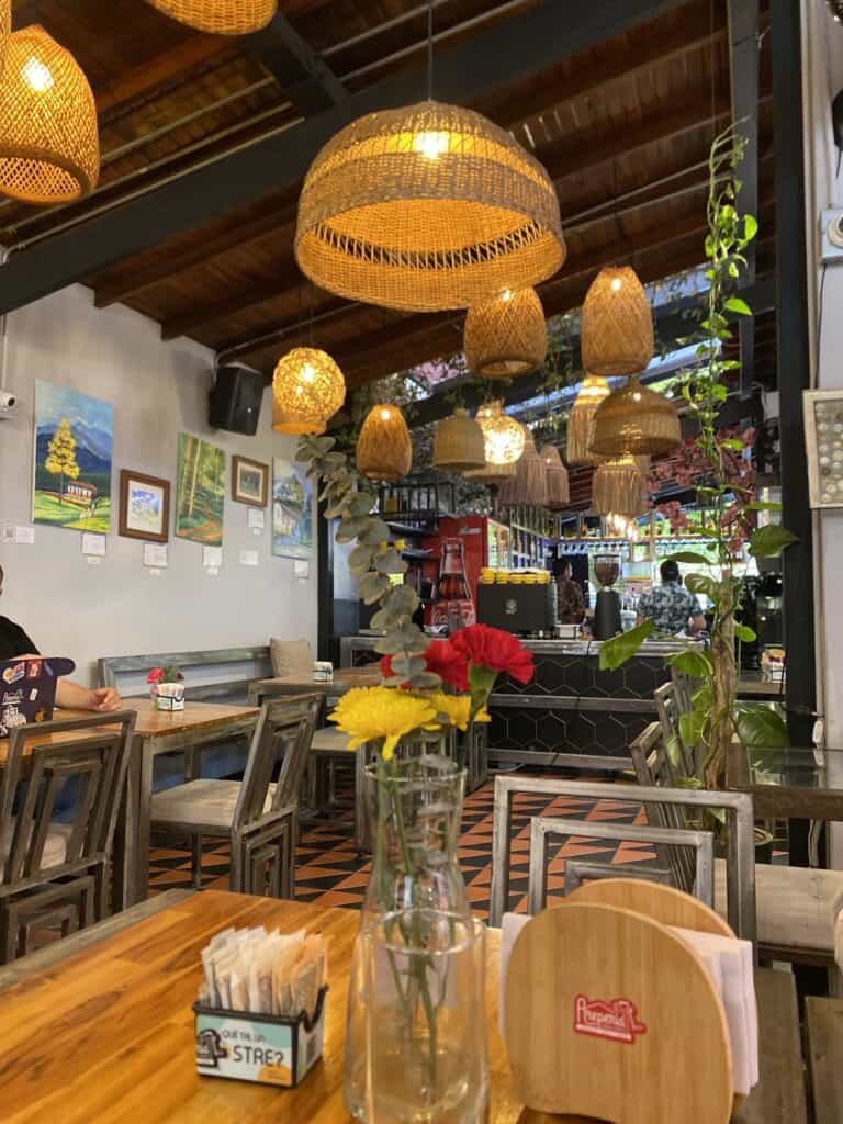 Interior de Arepería Casa Arte con decoración cálida, lámparas de mimbre y arte en las paredes, creando un espacio ideal para disfrutar de deliciosas arepas en un ambiente artístico y confortable.