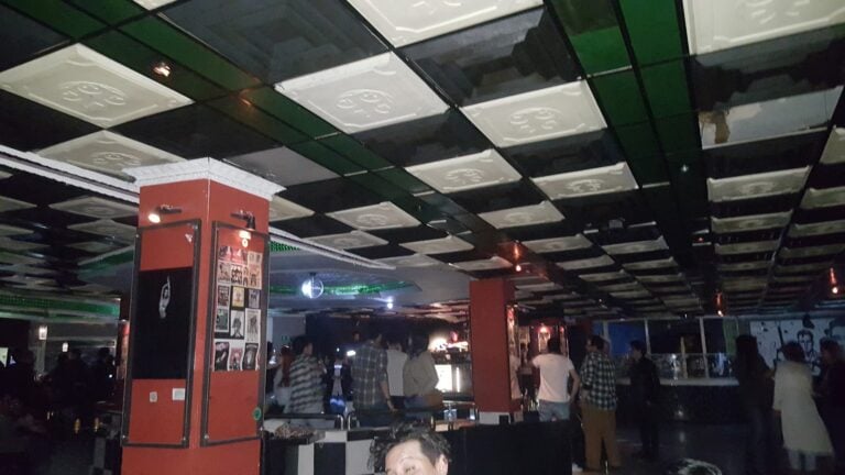 Imagen del Bar Asilo en un evento, mostrando un ambiente animado con clientes disfrutando de bebidas y música en un espacio moderno y bien iluminado.