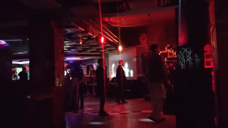 Interior del Bar Asilo en Bogotá, con ambiente nocturno, luces de neón y personas disfrutando de música y bebidas en un espacio moderno y vibrante.