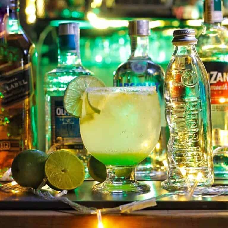 Cóctel refrescante en Bar de Tato con limones y botellas de licor, ideal para disfrutar en un ambiente de bar.