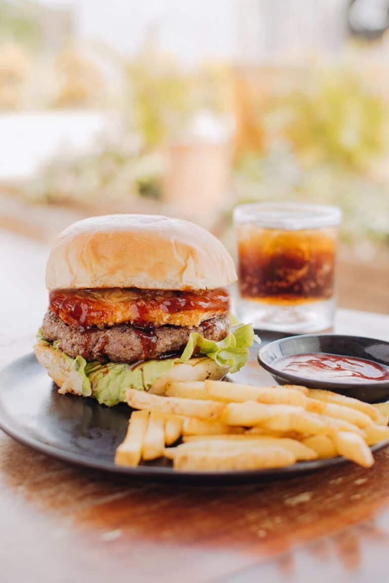 Hamburguesa jugosa con carne, lechuga, tomate y queso, acompañada de papas fritas y salsa. Perfecta para disfrutar en Casa Papau Resto Bar, un lugar ideal para comer bien y relajarse.
