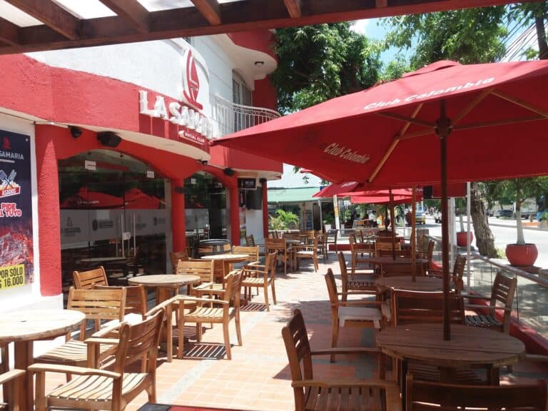 Exterior de La Samaria Social Club con mesas y sombrillas en una tarde soleada.