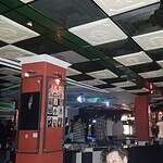 Interior del Bar Asilo con ambiente animado y clientes disfrutando de bebidas y música en un espacio moderno y acogedor.