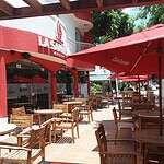 Exterior de La Samaria Social Club con mesas y sombrillas en la terraza, ideal para eventos sociales y reuniones en un ambiente acogedor y moderno.