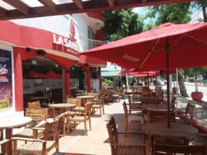 Exterior de La Samaria Social Club con mesas y sombrillas en la terraza, ideal para eventos sociales y reuniones en un ambiente acogedor y moderno.