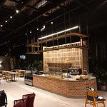 Amplia cafetería moderna en un evento campestre, con iluminación ambiental, mobiliario elegante y área de servicio con barra de ladrillo, ideal para eventos al aire libre y reuniones sociales.