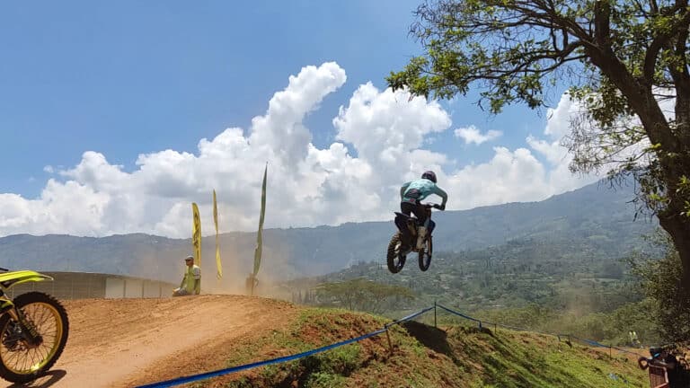 Motocross en la pista Guillermo Escobar, con un piloto en pleno salto durante una competencia en un día soleado.