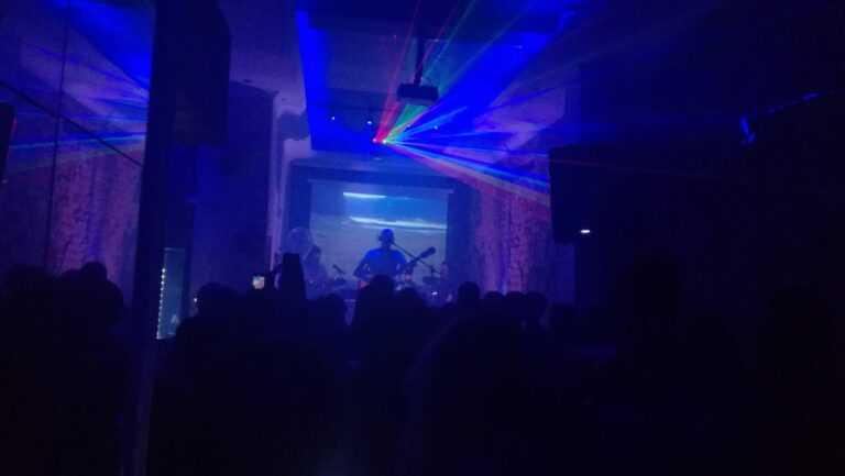 Espectáculo en vivo de Radio57 con luces de colores y música en un entorno oscuro y enérgico.