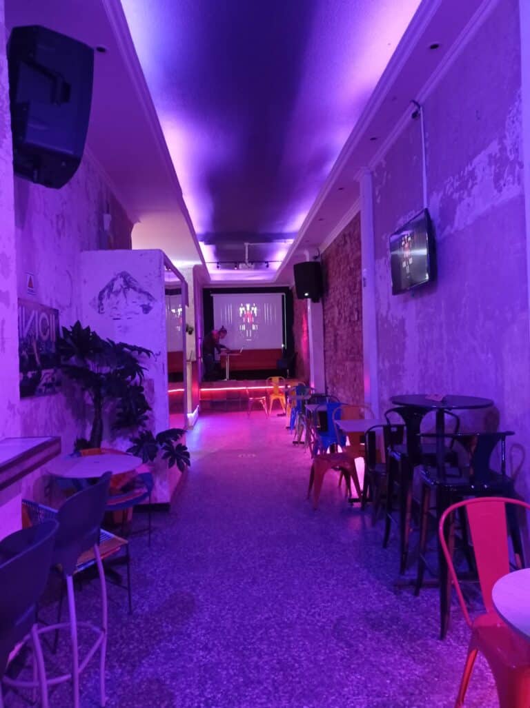 Ambiente de evento con iluminación morada, mobiliario variado y pantallas, ideal para presentaciones y reuniones en Radio57.