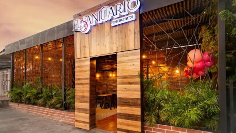 Fachada del Restaurante El Santuario con diseño moderno y acogedor, rodeada de vegetación y detalles en madera, ideal para una experiencia gastronómica en un ambiente natural y elegante.