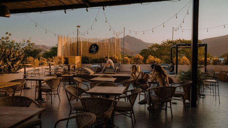 Terraza del Viajero Santa Marta con vista a las montañas, ideal para disfrutar de bebidas y buena compañía en un ambiente relajado y con decoración moderna.