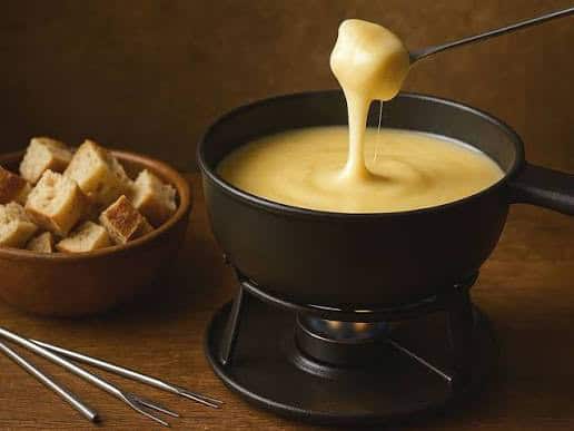Queso fundido en fondue con pan crujiente para compartir en noche especial.