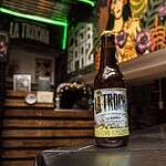 Botella de cerveza en un bar con decoración colorida y arte mural.