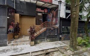 Fachada del restaurante Morena Vice en una calle urbana, con entrada en la parte superior y plantas decorativas en el exterior.