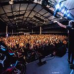 Espectáculo en vivo en el Centro de Eventos y Exposiciones, con una gran audiencia disfrutando de música y entretenimiento en un ambiente vibrante y moderno.