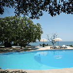 Piscina en Casa Kapikua, rodeada de árboles y con vista al mar, ideal para relajarse y disfrutar del paisaje en un entorno exclusivo y tranquilo.