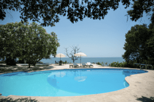 Piscina en Casa Kapikua, rodeada de árboles y con vista al mar, ideal para relajarse y disfrutar del paisaje en un entorno exclusivo y tranquilo.