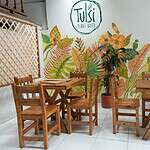 Imagen de área de comedor con mobiliario de madera en un restaurante vegetariano Tulsi.