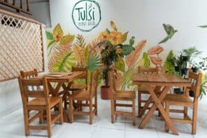Imagen de área de comedor con mobiliario de madera en un restaurante vegetariano Tulsi.