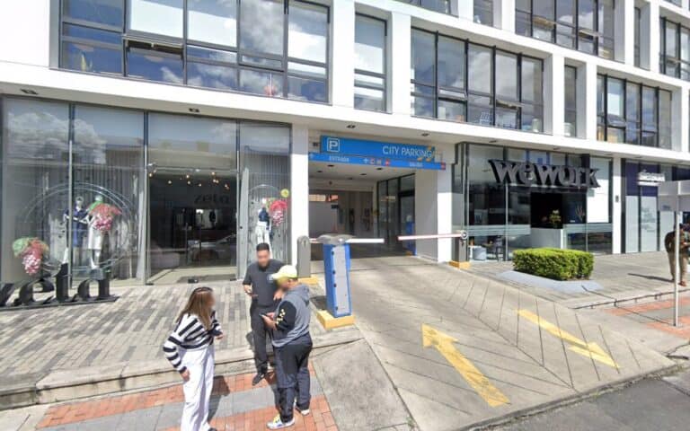 Entrada principal de TRES60LAB en Ciudad Empresarial, con acceso peatonal y estacionamiento cercano, en un edificio moderno con grandes ventanales y señalización clara.